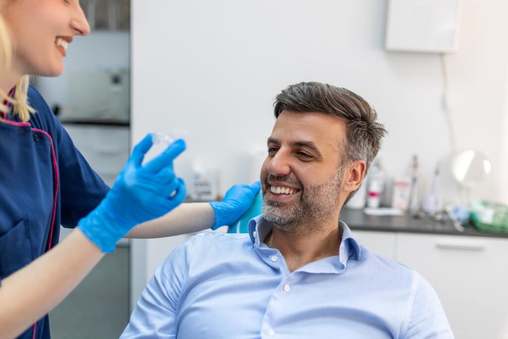 Patient smiling at dentist holding clear aligner