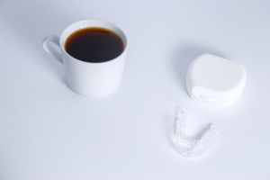 a cup of coffee sitting next to an Invisalign tray